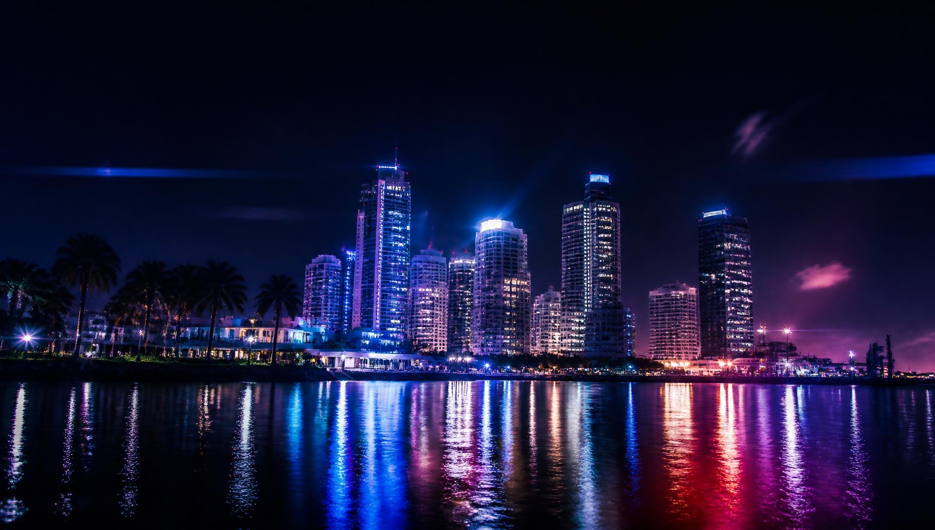 Miami skyline at night with neon reflections on the water
